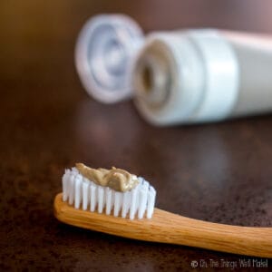 Homemade clay-based natural toothpaste (without cacao) shown on bamboo toothbrush.