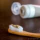 Homemade clay-based natural toothpaste (without cacao) shown on bamboo toothbrush.