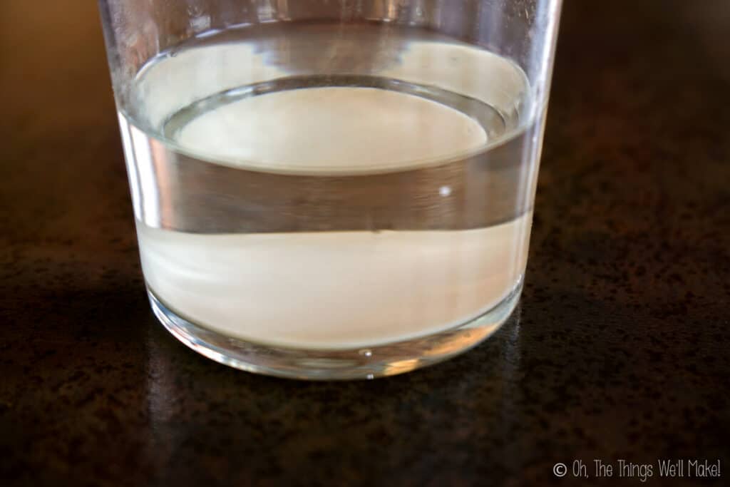 a glass with liquid in it with a powder that has sunk to the bottom