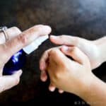 spraying a homemade hand sanitizer onto hands that are being rubbed together.