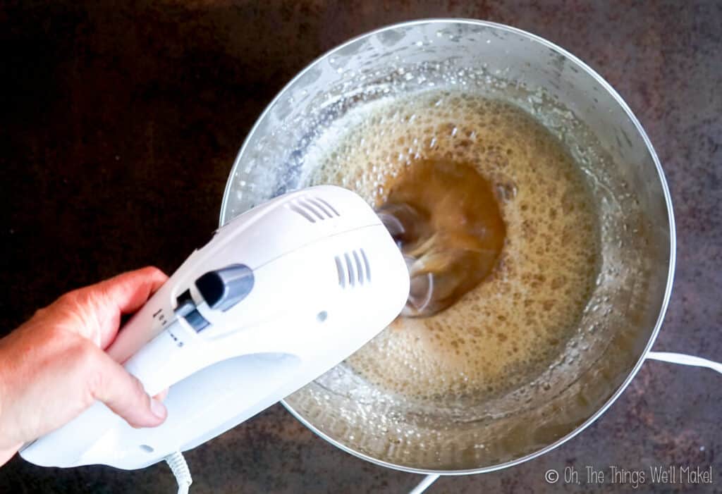 Overhead view of an electric beater whipping the honey gelatin mixture.