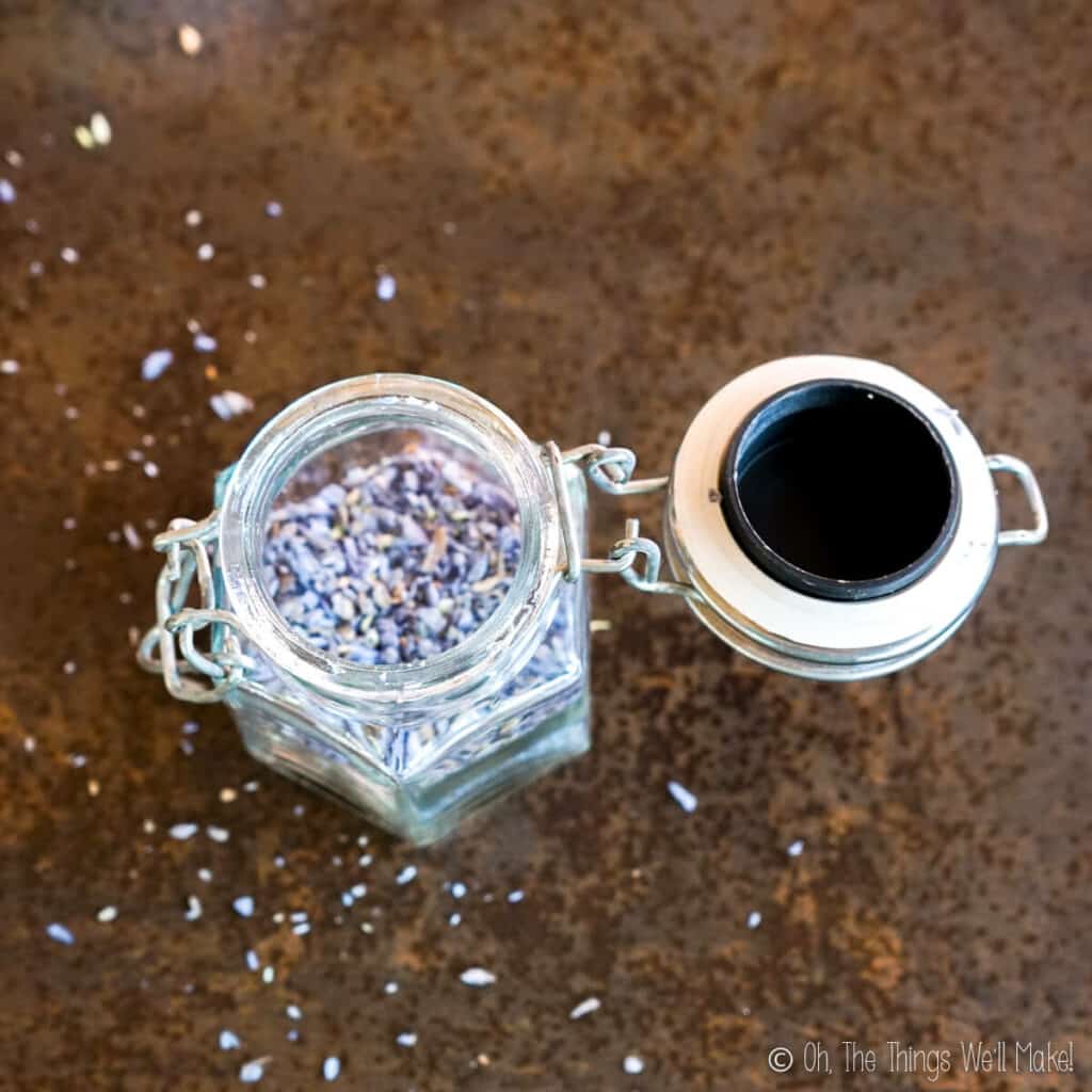 Overhead view of indigo blue coconut sprinkles in an open jar, with more sprinkles over the surface below it.