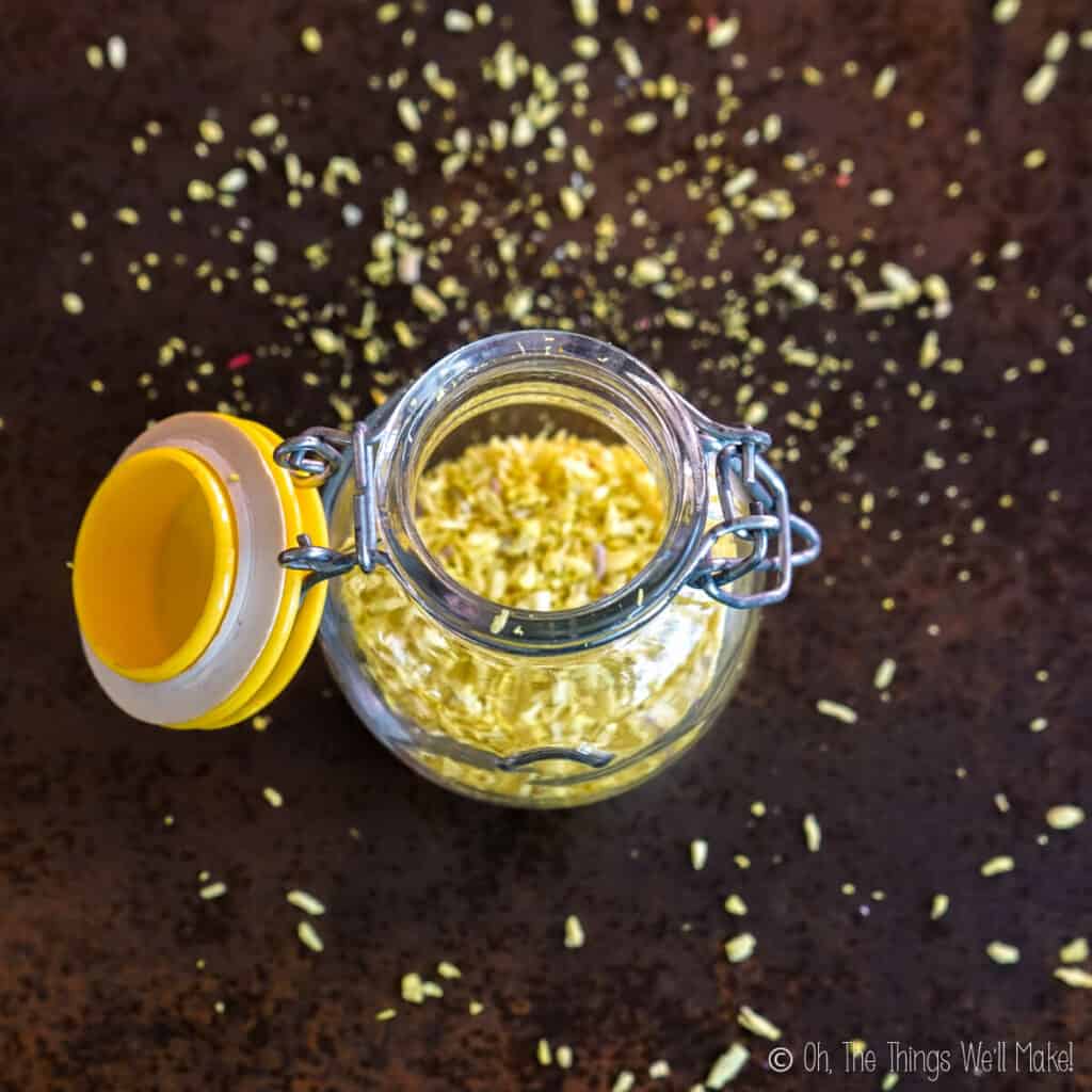Overhead view of yellow coconut sprinkles in an open jar, with sprinkles over the surface below it.