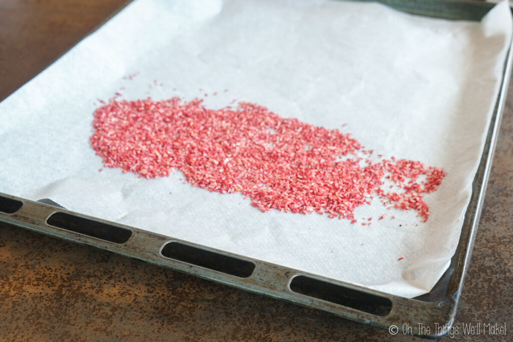 Colorful pink sprinkles spread over a baking tray lined with paper