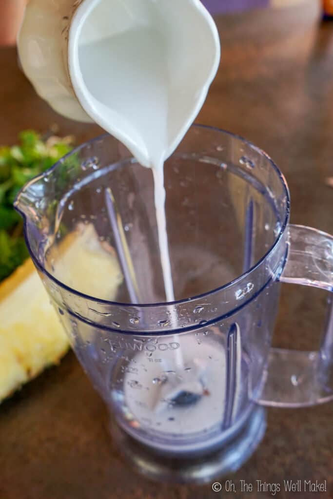 pouring coconut milk into a blender cup
