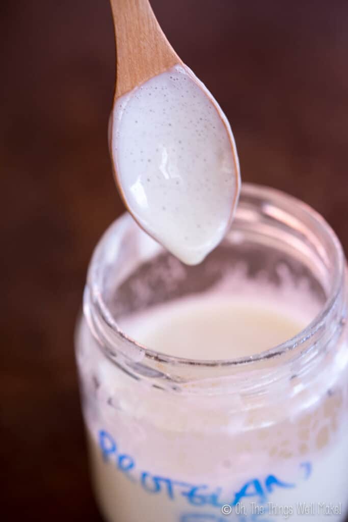 A jar of lotion made with Protelan ENS emulsifier, showing how the lotion drips off a spoon into the jar