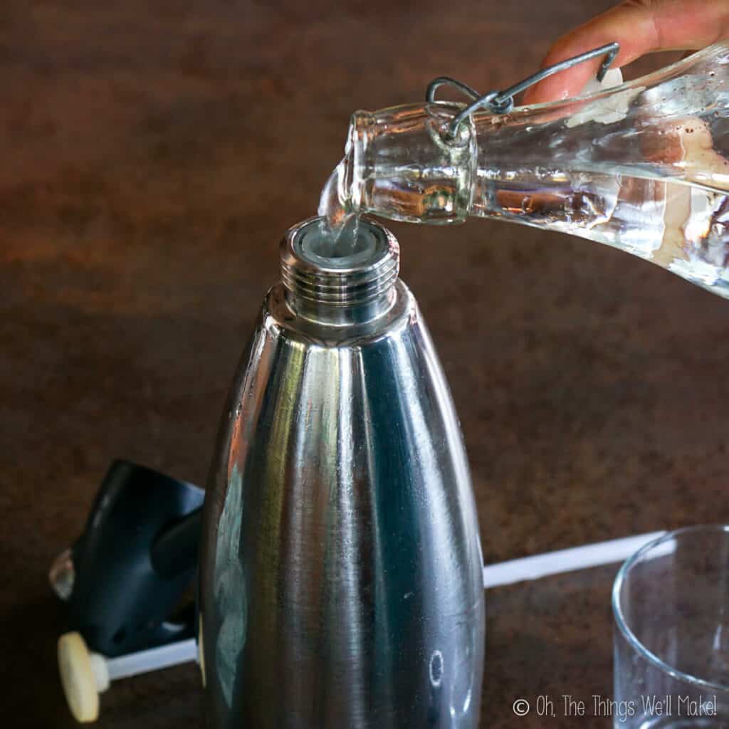 Pouring water into the bottle of a soda siphon.