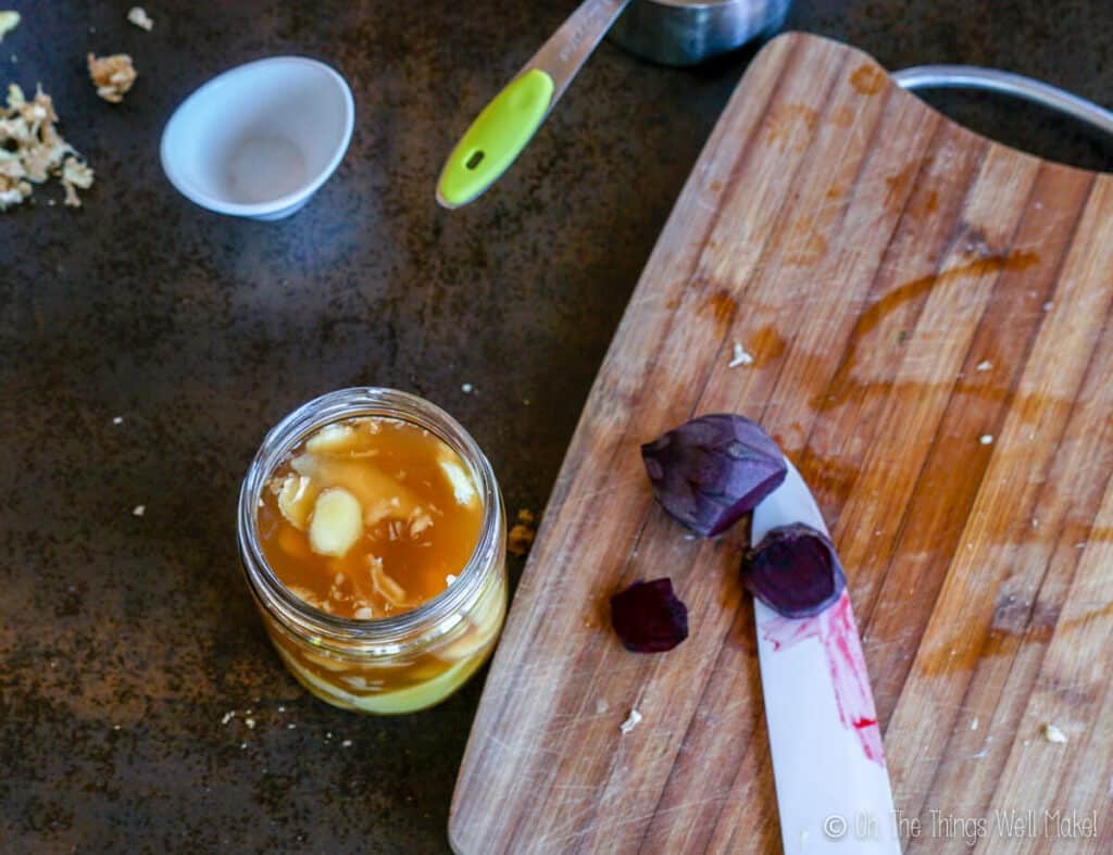 Slicing beetroot on a bamboo cutting board next to the jar of pickled ginger.