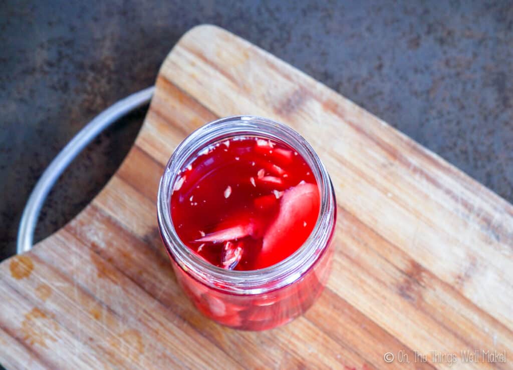 Overhead view of sliced ginger in vinegar which has been tinted pink with beetroot slices.