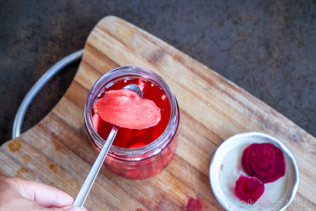 Spooning out a pink ginger slice from a jar of pickled ginger.