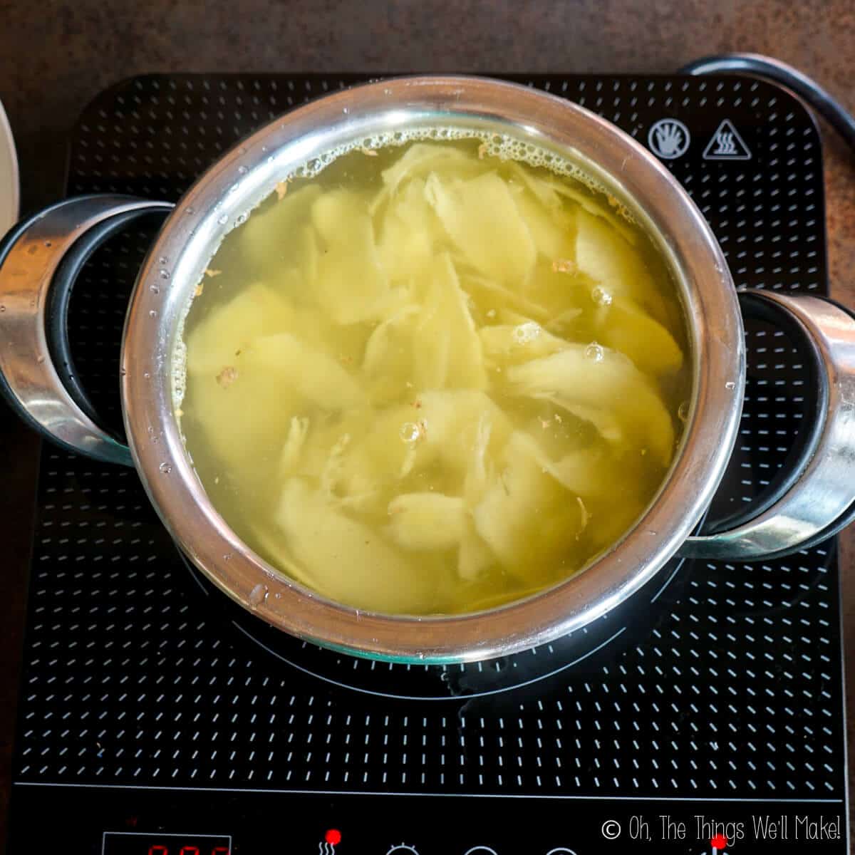 Boiling the ginger in water in a stainless steel pot.