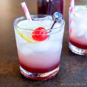 Closeup of a Shirley Temple Drink, garnished with a lime slice and Maraschino cherry