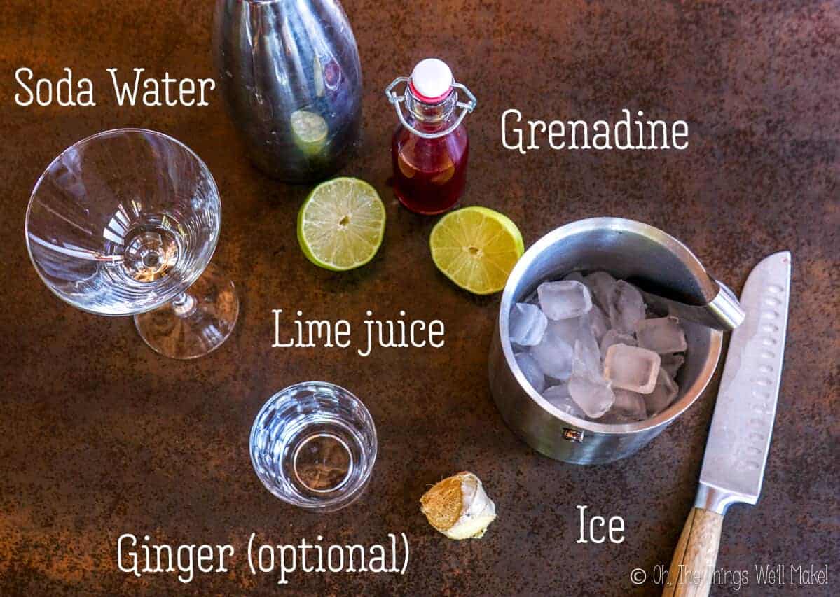 overhead view of the ingredients for a Shirley Temple Drink: lime, grenadine, ginger, ice, soda water