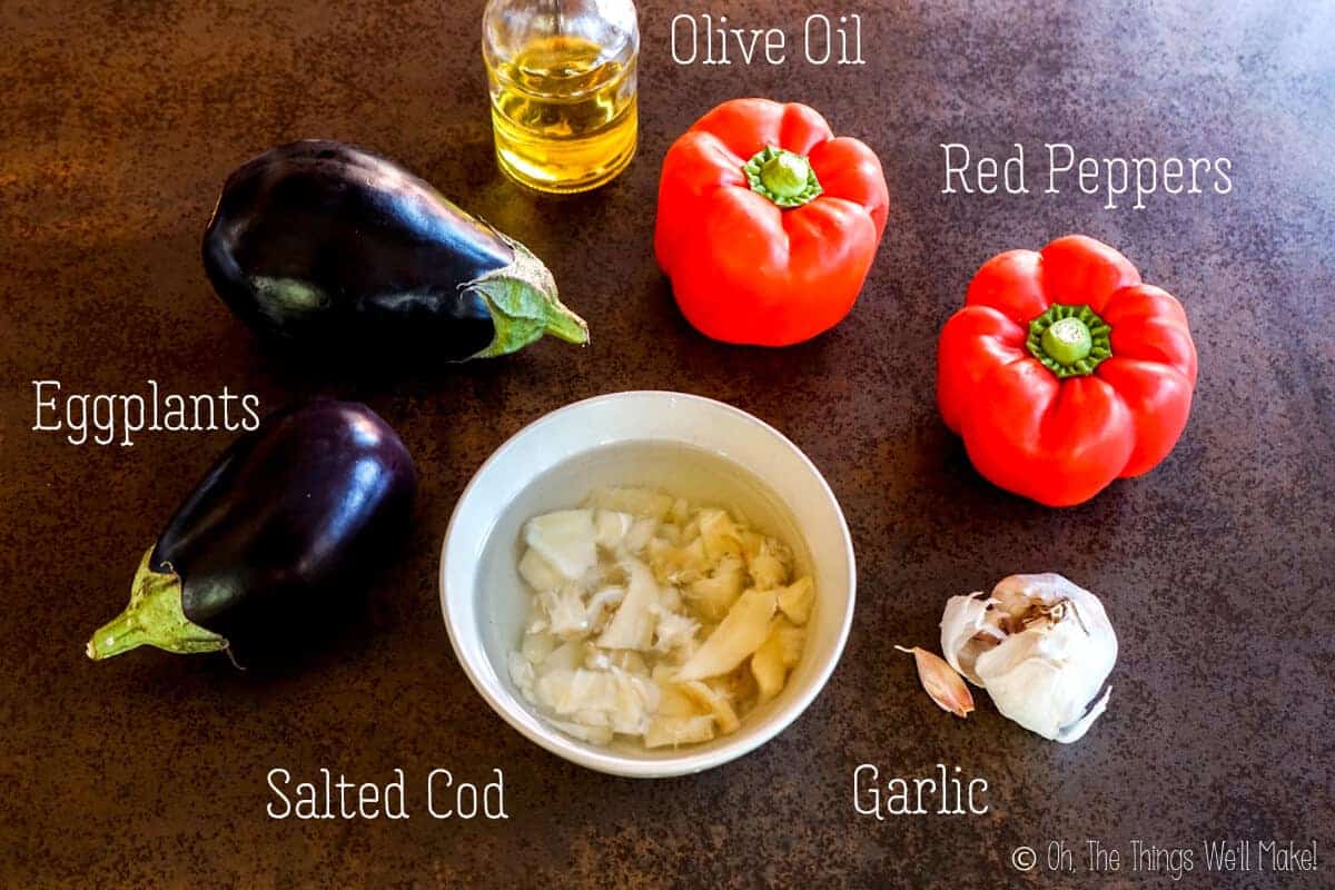 Overhead view of the ingredients for espencat: red peppers, eggplants, salted cod, olive oil, and garlic