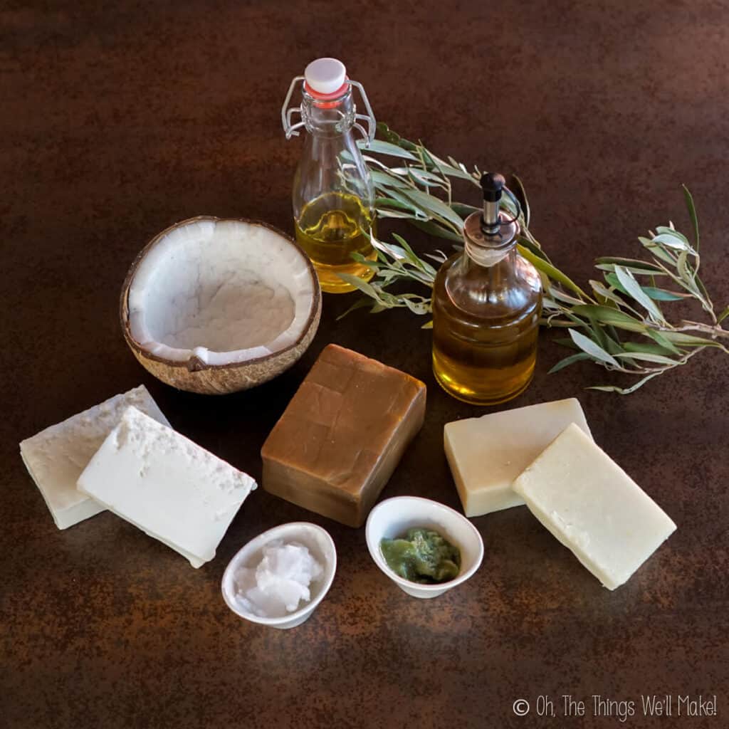 Several oils in bottles and bowls near some homemade soaps