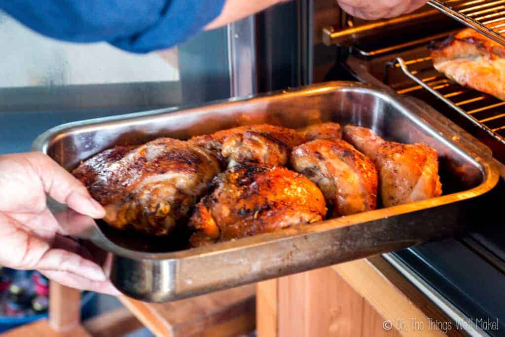 Roasted turkey pieces in a pan, being removed from the oven