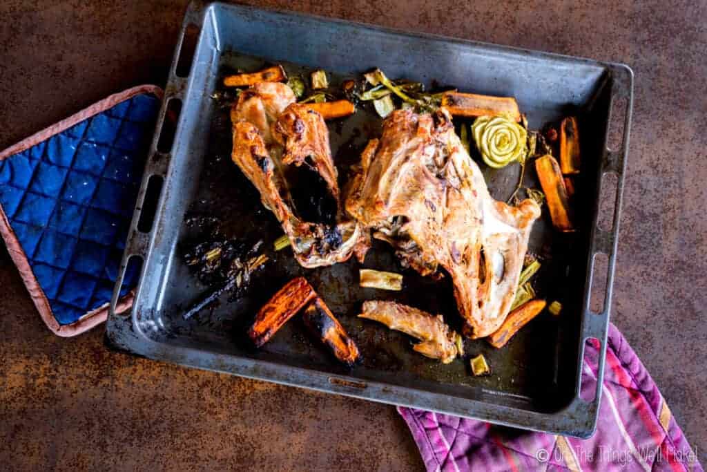 Overhead view of roasted turkey carcass on a tray with roasted vegetables
