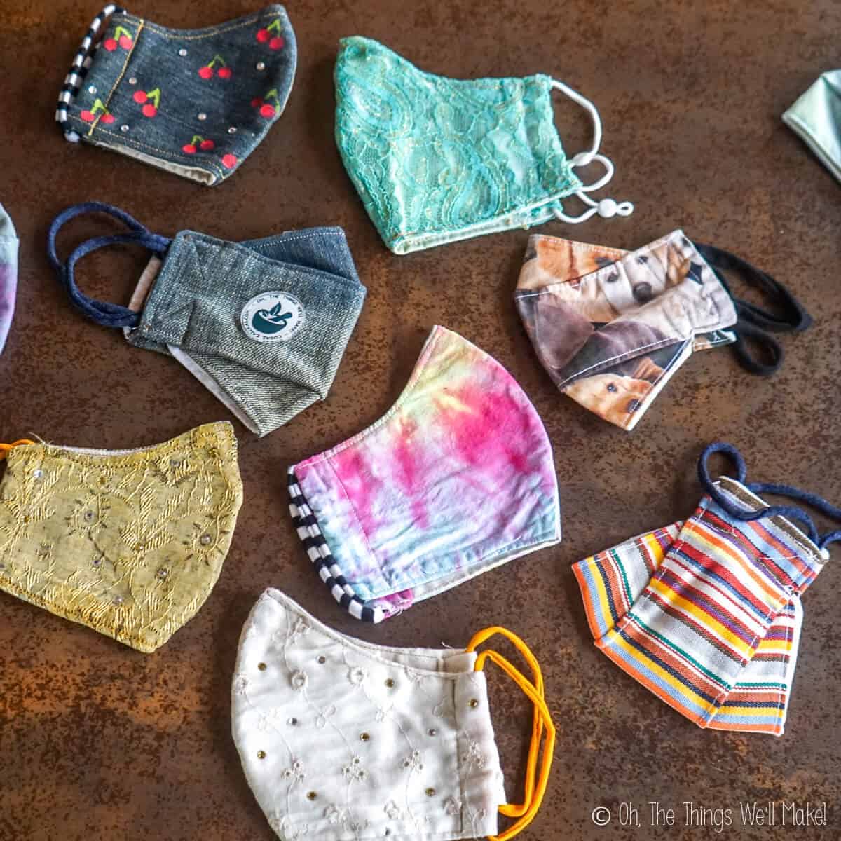 Overhead view of a variety of fun face masks, tie dyed masks, denim masks, lace masks, etc.