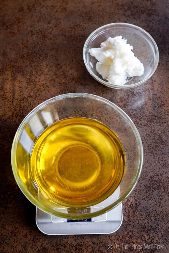 A bowl of solid coconut oil next to a bowl filled with olive oil on a scale. 