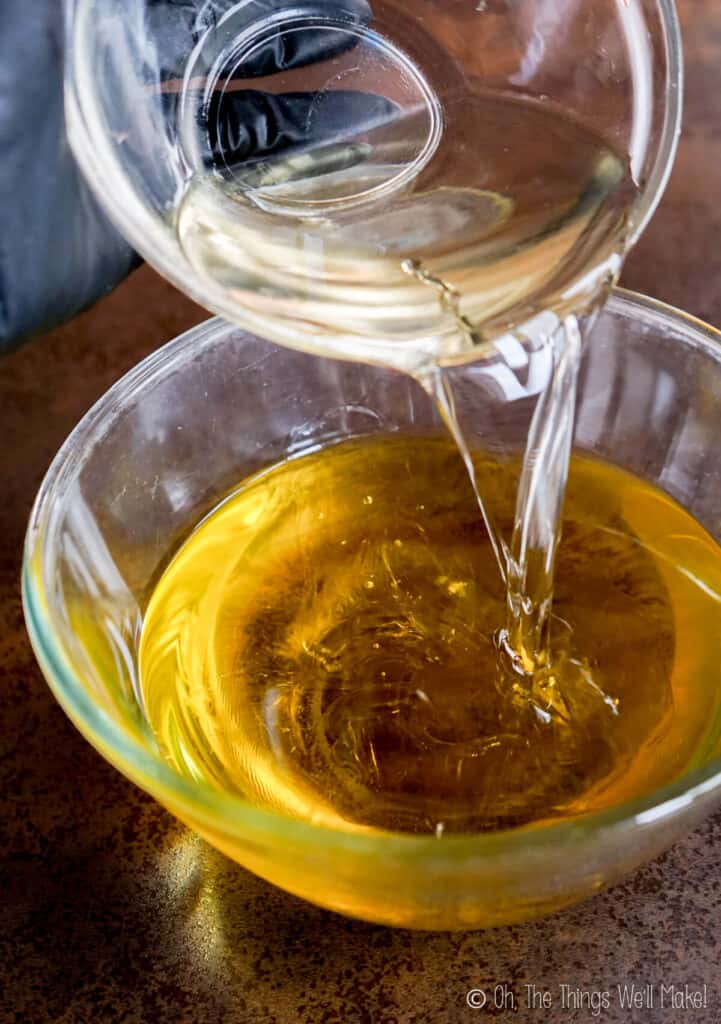 Pouring coconut oil into a bowl with olive oil.