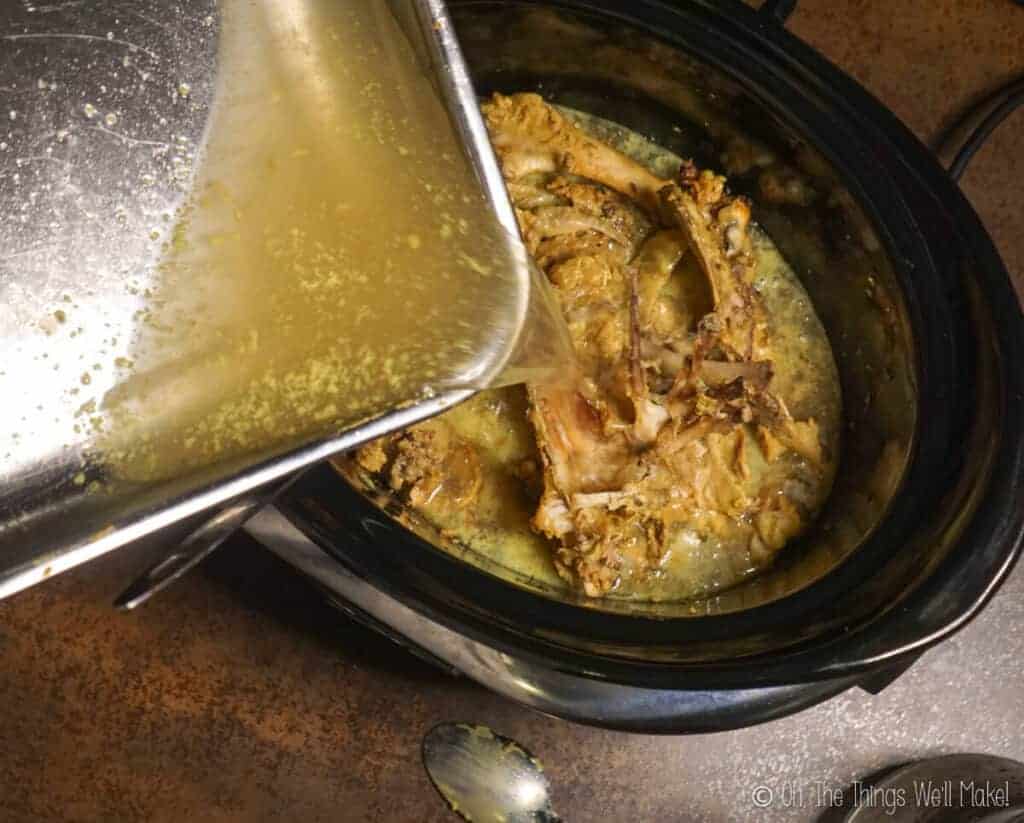 Adding more water to the bones in the slow cooker to cover them