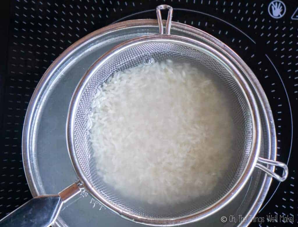 Overhead view of rice in a strainer, soaking in water