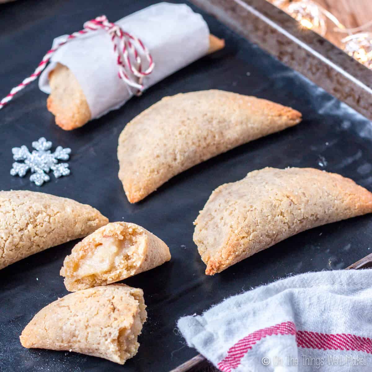 Homemade pastissets, a dessert empanadilla filled with a sweet boniato filling, on a baking tray with one broken open to show the filling.