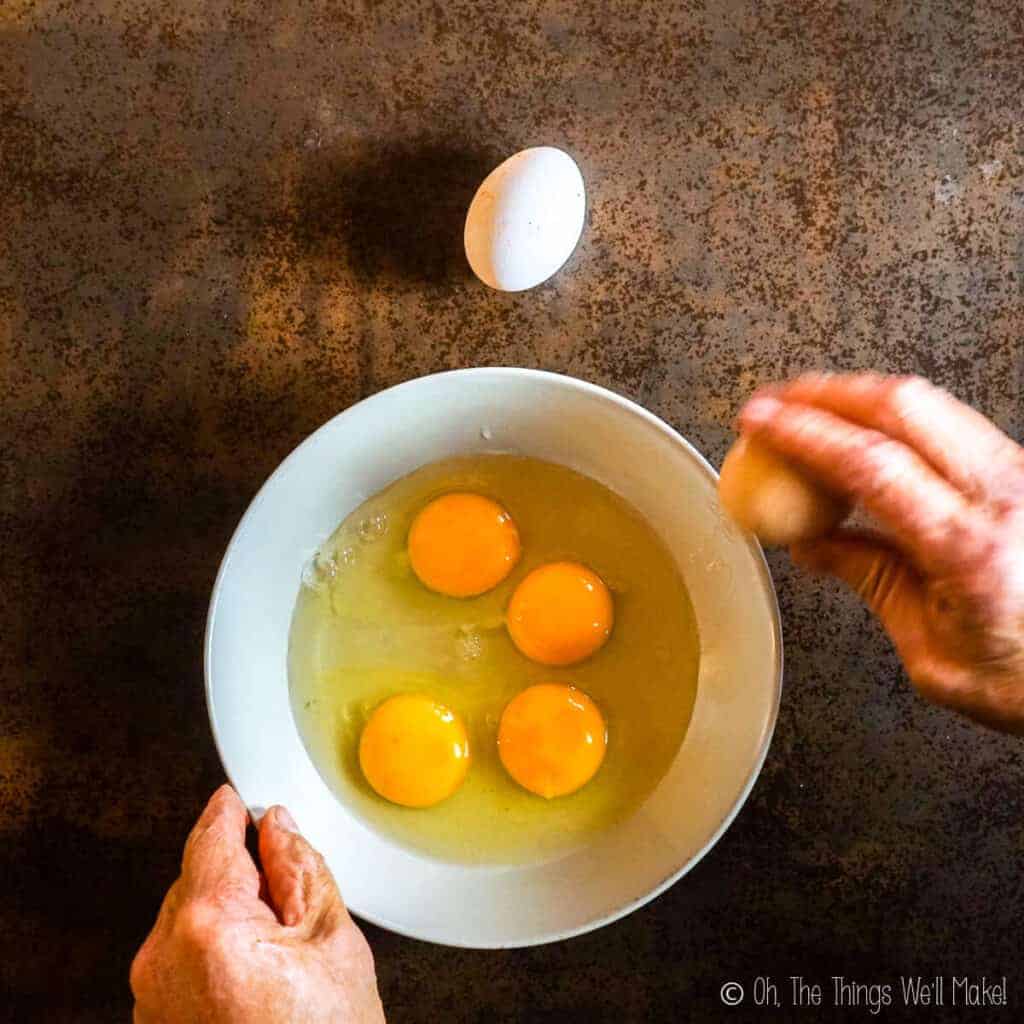 Breaking the eggs and adding them to a bowl