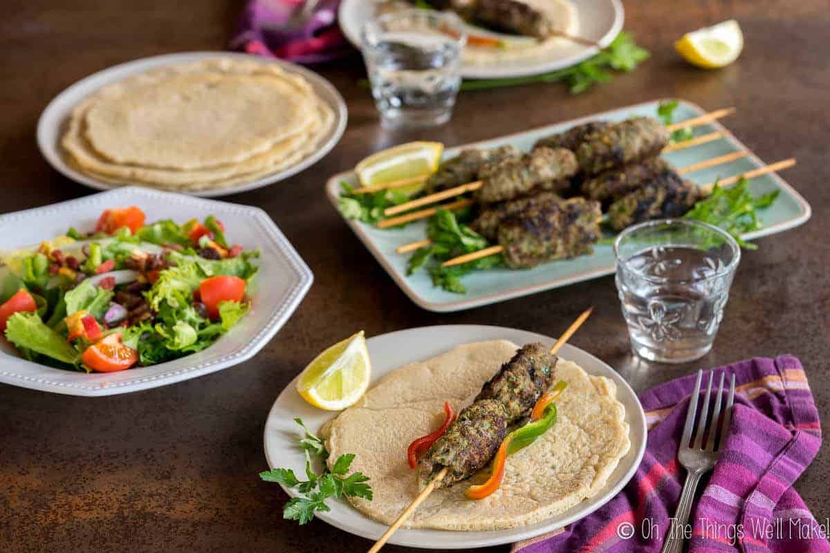 A beef kafta kebab on a pita in front of a stack of cooked kafta.