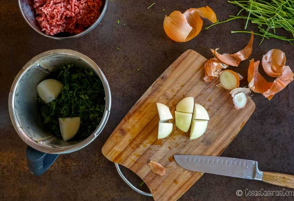 Cutting onions on a cutting board, and adding them to a food processor