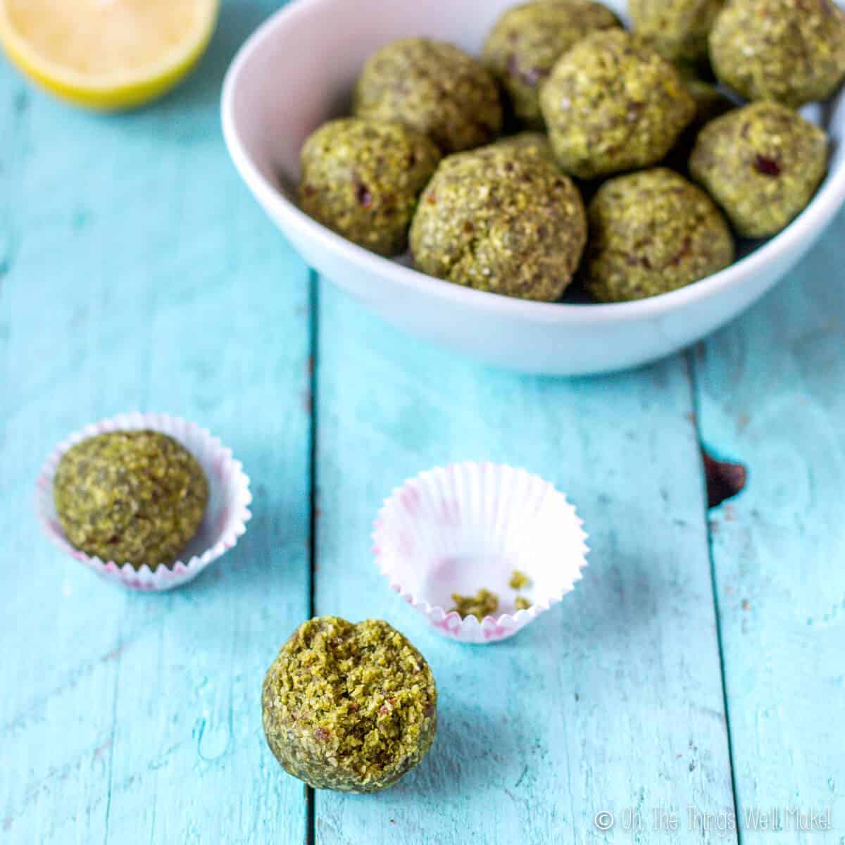 Matcha coconut lime balls in a bowl, with two balls in front of the bowl.