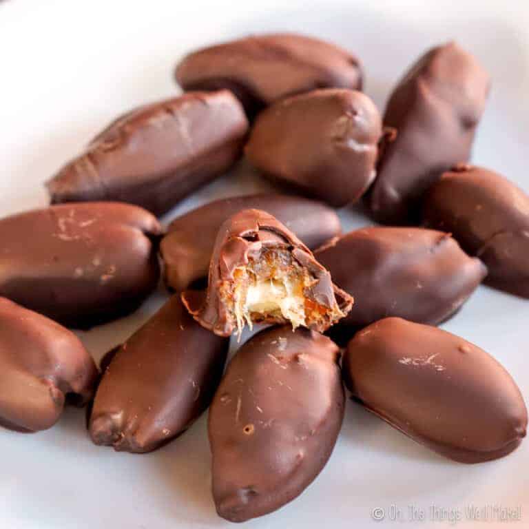 Closeup of a pile of chocolate dates with almonds, focusing on one that is bit open