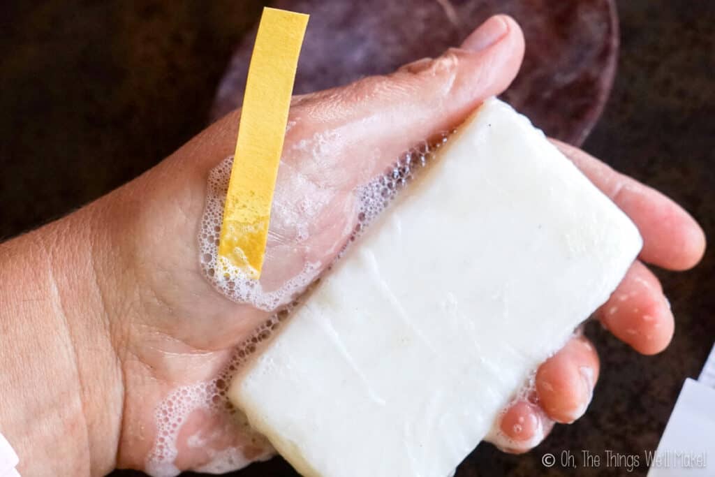 lathering a shampoo bar and using a test strip to test the pH of the lather