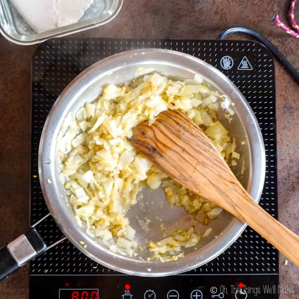 cooking the chopped onion, minced garlic, and ginger in a frying pan