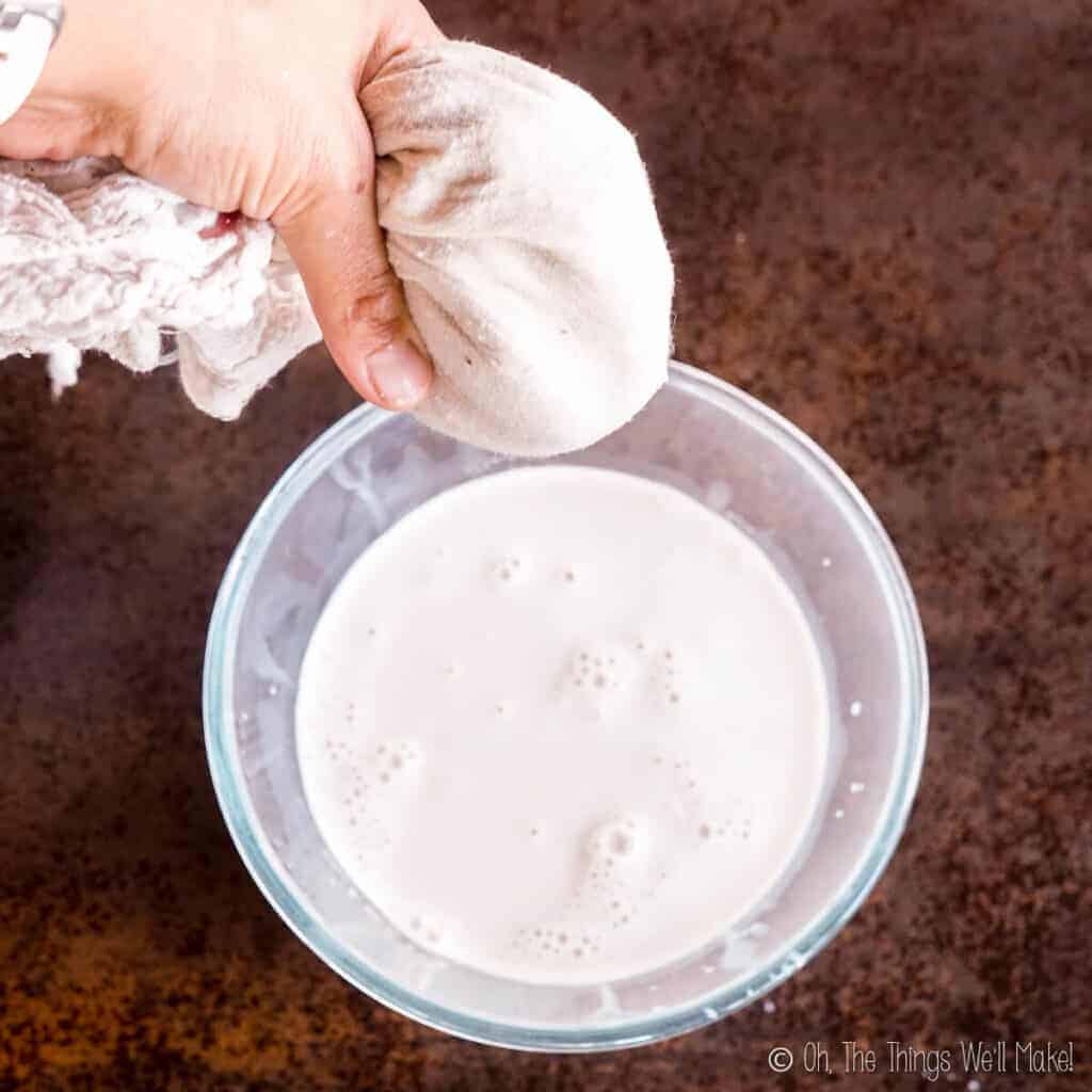 straining the pulp from the tigernut milk with a cotton cloth held over a bowl of tigernut milk