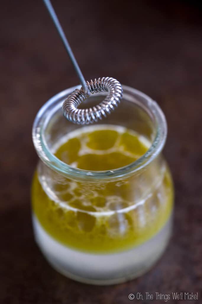 a milk frother held over a jar with ingredients for a homemade moisturizer