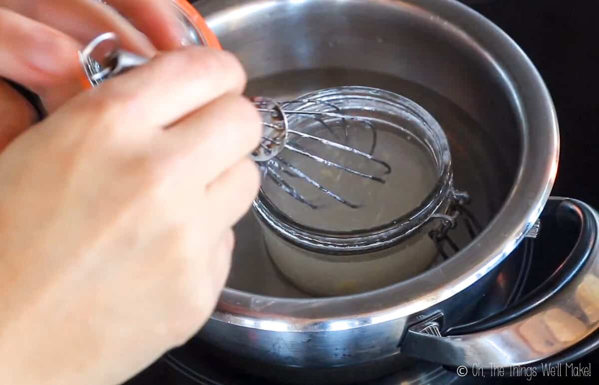 whisking a homemade hair gel in a pan of water on the stove.