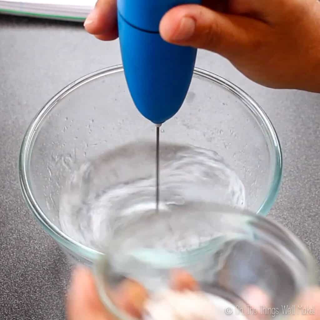 blending a bowl of water with a milk frother before adding in the xanthan gum powder