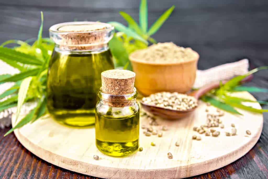 hemp seed oil on a wooden board next to hemp seeds