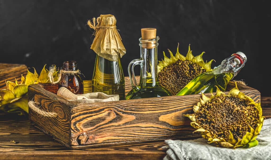 A wooden box with bottles of sunflower oil and sunflowers