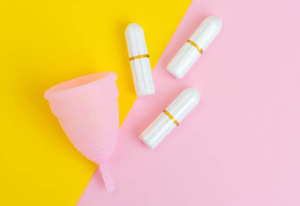 A menstrual cup next to three tampons