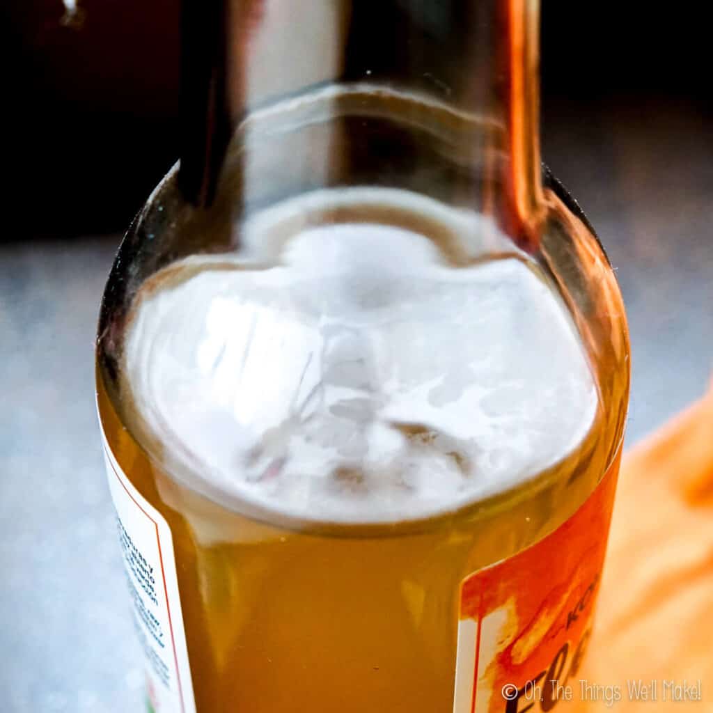A bottle of store bought kombucha with a thin skin forming on the surface