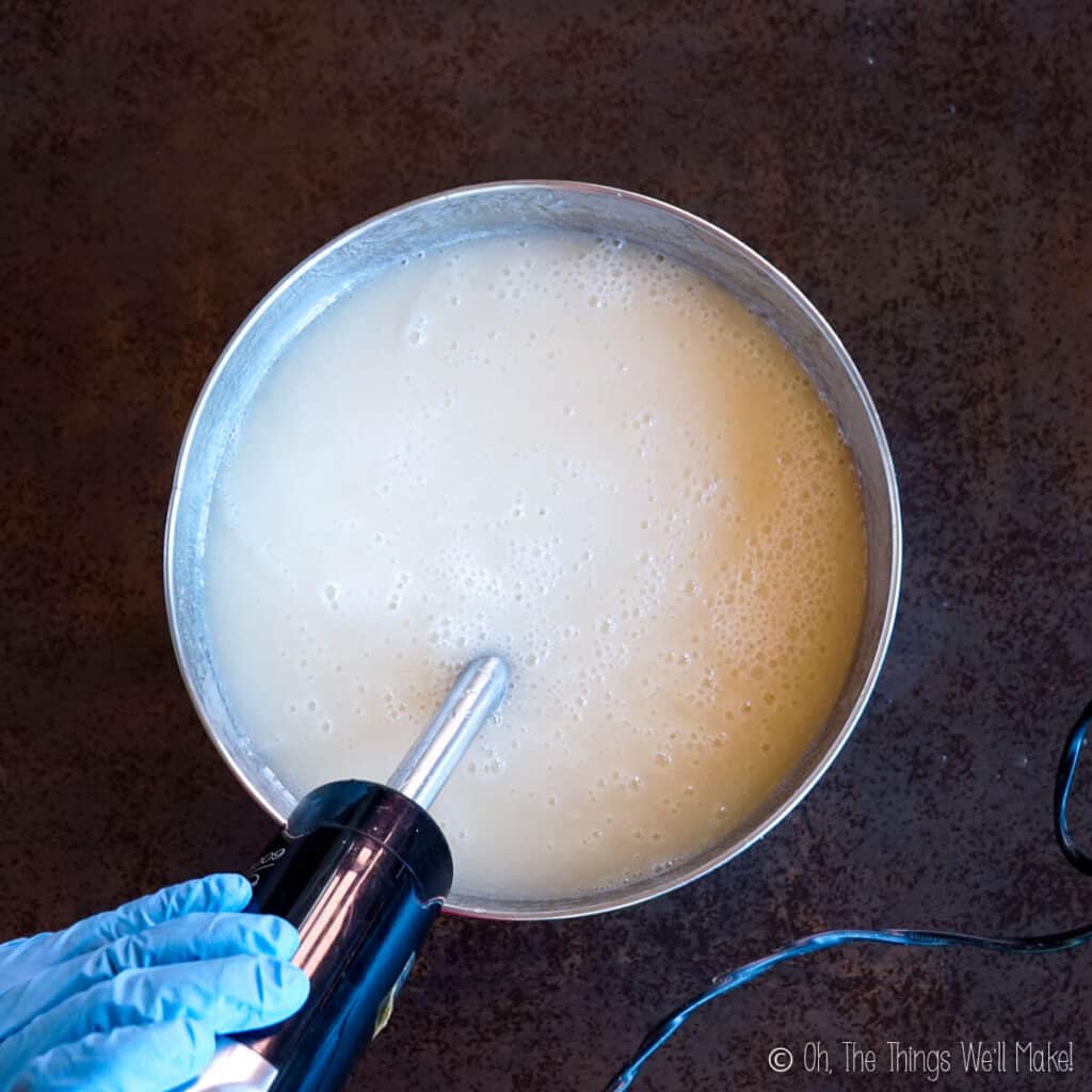 A creamy soap mixture in a bowl with an immersion blender