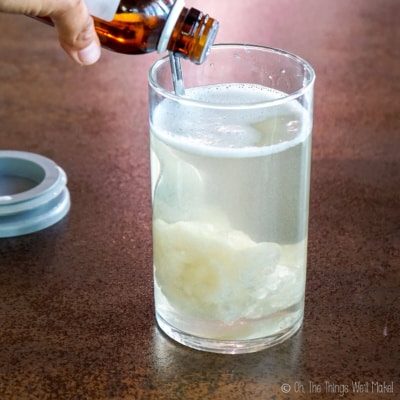 pouring essential oils into a container with water and liquid soap paste.