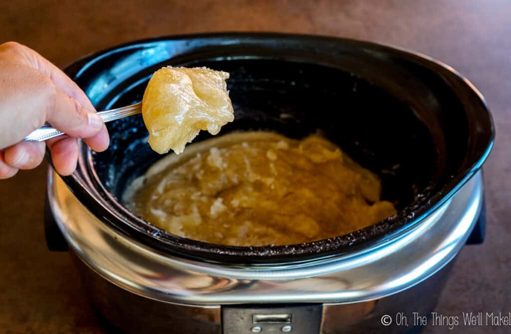 photo of a cooked soap paste on a spoon over a slow cooker