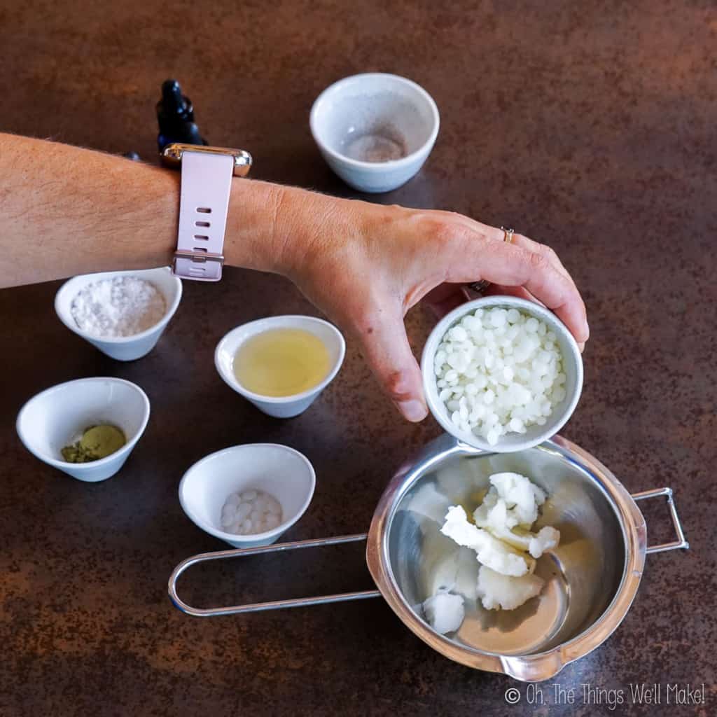 Pouring beeswax pellets into a double boiler insert with shea butter in it.