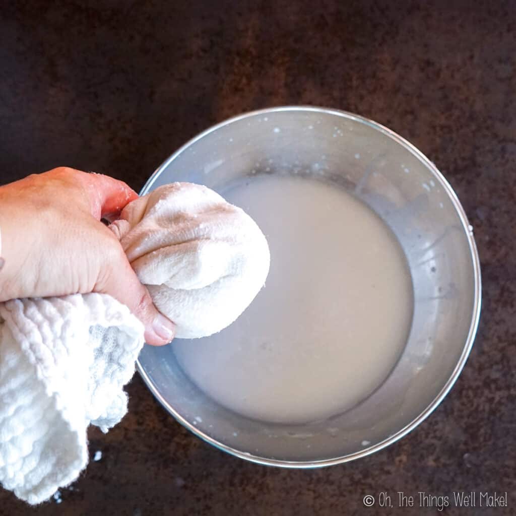 straining out the finished coconut milk from a cloth into a bowl.