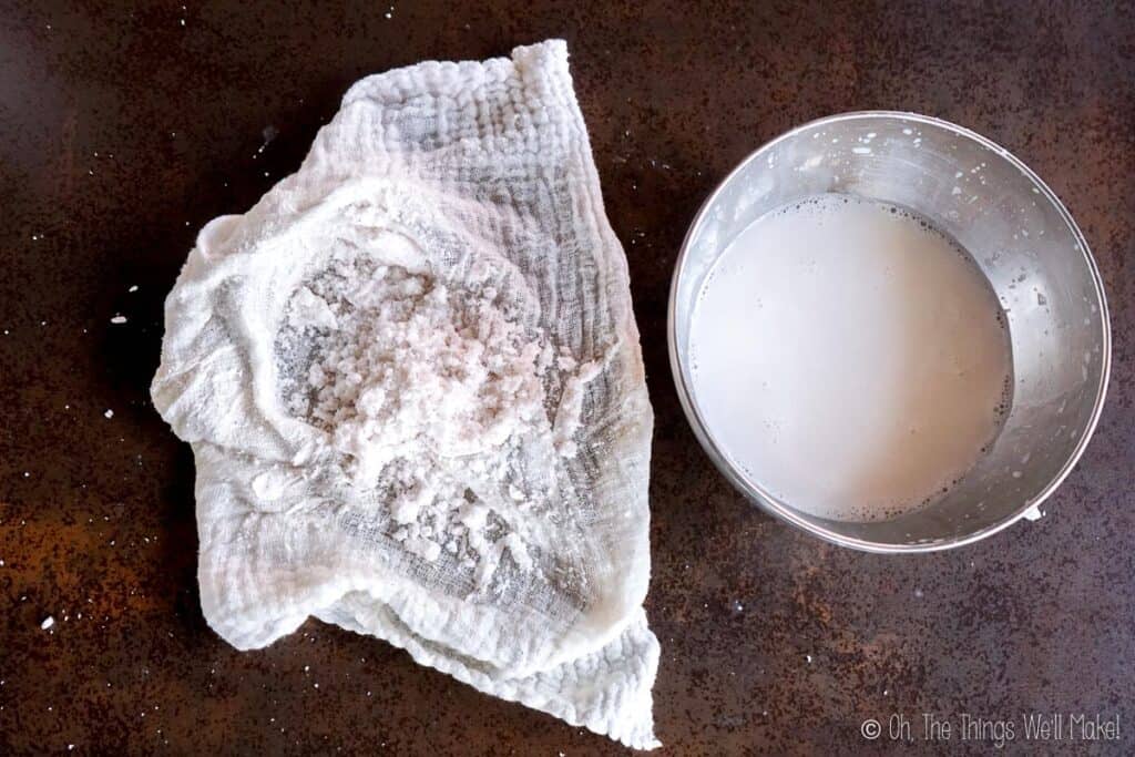 An open cloth with coconut pulp in it next to a bowl of coconut milk