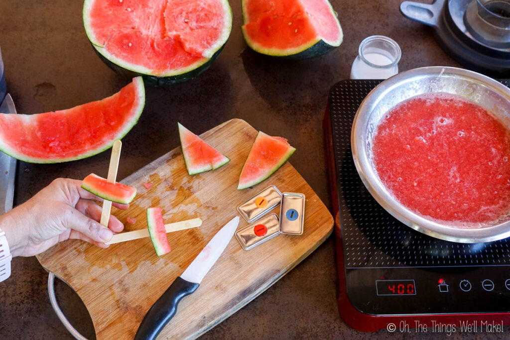 overhead view of watermelon rinds on cutting board with popsicle sticks