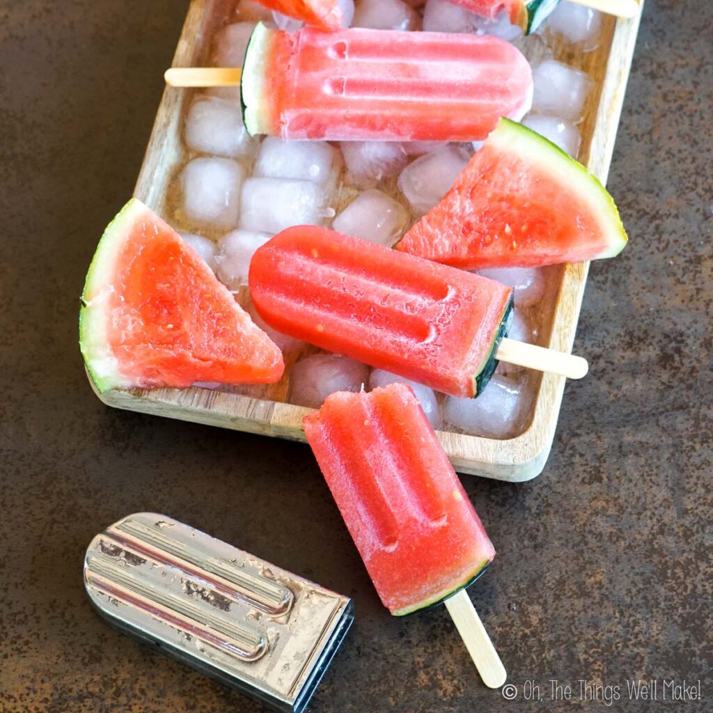 watermelon gelatin popsicles on a tray with ice.